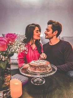 a man and woman sitting at a table with a cake