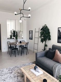 a living room filled with furniture next to a dining table and mirror on the wall