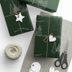 presents wrapped in green paper and tied with twine are sitting on a table next to scissors