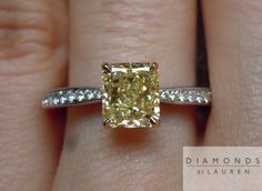 a woman's engagement ring with a yellow diamond in the center and white diamonds around it