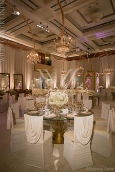 an elegant wedding reception with white linens and chandelier draped over the tables