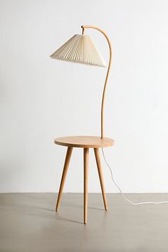 a table lamp sitting on top of a wooden stand next to a white wall and floor