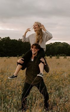 a man carrying a woman on his back in the middle of a field with tall grass