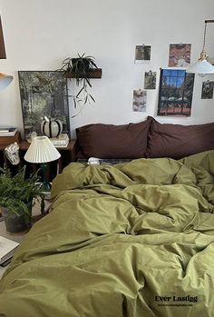 an unmade bed in a room with pictures on the wall above it and a lamp next to it