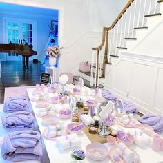 a room filled with lots of baby items on top of a white table next to a stair case