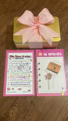 a pink bow on top of a gift box next to a notepad and pen