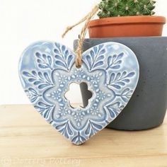 a heart shaped ceramic decoration next to a potted plant