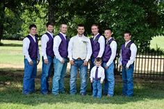 a group of young men standing next to each other in front of a lush green field