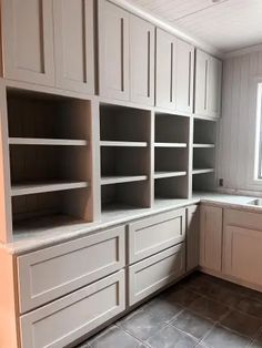 an empty kitchen with white cabinets and tile flooring