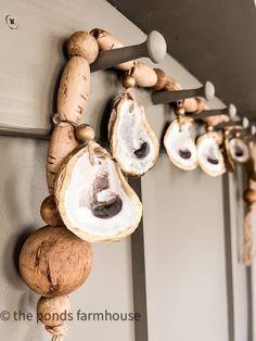 oyster shell garland with diy faux fishing corks hanging on the wall and text overlay reading how to make oyster shell garland with diy faux fishing corks