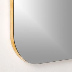 a mirror hanging on the wall with a wooden frame and gold trim around it's edge