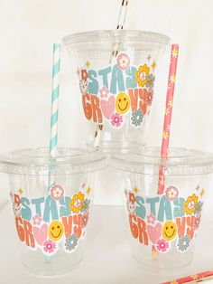 four plastic cups with straws in the shape of flowers and smiley faces on them