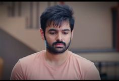 a man with black hair and beard wearing a pink shirt