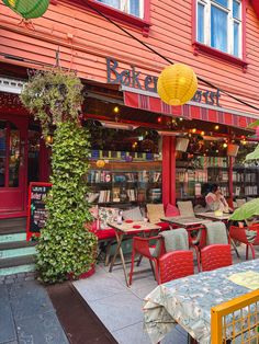 tables and chairs are outside in front of a book store with yellow lanterns hanging from the roof