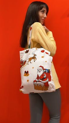 a woman carrying a santa clause bag in front of a red wall