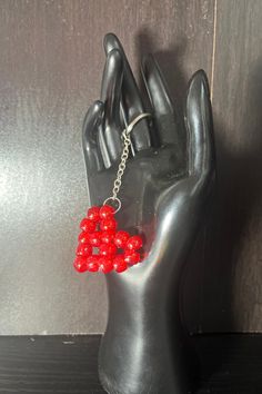 a pair of red beaded earrings on a black mannequin's hand