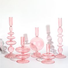 a group of pink glass vases sitting next to each other on a white surface