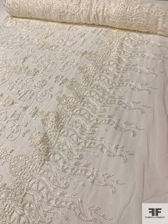 an image of a bed that is made with white linens and lace on it