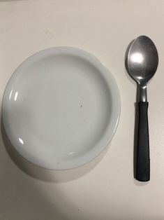 a white plate with a spoon and knife next to it