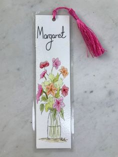 a bookmark with flowers in a vase and the word margaret on it