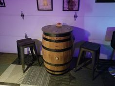 a wine barrel table and stools in a room with purple lighting on the walls