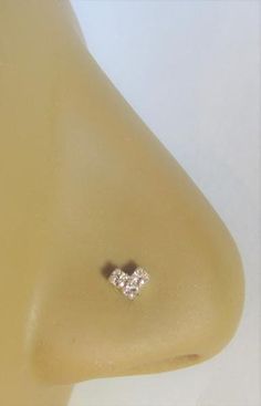 a pair of diamond stud earrings sitting on top of a mannequin