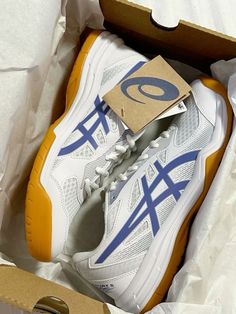 a pair of white and blue tennis shoes in a box with the shoe tag on it