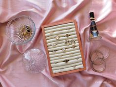 an assortment of jewelry and wine on a pink cloth