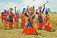 a group of people dressed in colorful costumes standing on top of a dry grass field