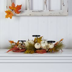 a white mantle with candles and fall leaves