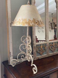 a lamp sitting on top of a wooden table next to a mirror and dresser in a room