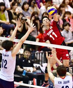 two men playing volleyball in front of an audience