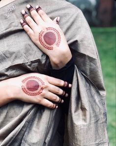 two women with tattoos on their arms and hands, one holding the other's shoulder