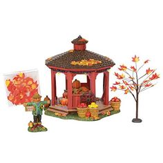 a small red gazebo sitting next to a tree with fall leaves on it's branches