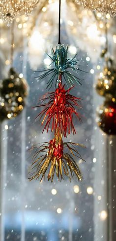 christmas decorations hanging from the ceiling in front of a window with snow falling on it