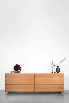 a large wooden dresser sitting on top of a floor next to a vase with flowers