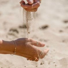 someone is throwing sand into the air with their hands on top of it in the sand