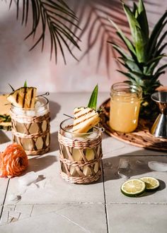 two glasses filled with drinks sitting on top of a table next to some sliced fruit