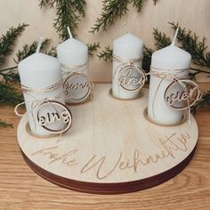 three votive candles are sitting on a wooden plaque with the word love written on it