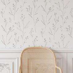 a chair sitting in front of a wall with flowers painted on the wall behind it