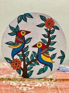 two birds sitting on top of a tree with leaves and flowers painted on the side