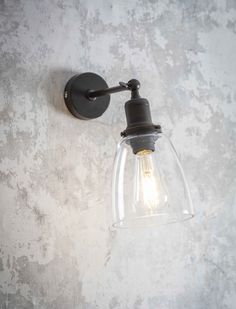 a light that is on the wall next to a cement wall with a glass shade