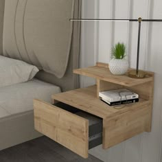 a nightstand with a plant on it next to a bed