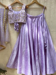 A three-piece lavender kyra tassel lehenga set from the Priti Sahni collection. This elegant lavender raw silk lehenga is paired with lavender blouse in raw silk fabric with resham, zari and sequin floral hand embroidery. The lehenga has side hanging tassels to the waistline. And the blouse has a tassel tie-up at the back. The outfit is completed with a tulle lavender net dupatta with sequin scalloped edging. Simple Stiched Lehenga, Lavender Crop Top Outfit, Lavender Color Dress, Lehenga Simple, Lavender Lehenga, Lengha Blouse, Ivory Lehenga, Evening Dress Outfit, Hanging Tassels