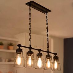 a chandelier with five light bulbs hanging from it's ceiling in a kitchen