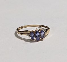 10k Solid Gold Tanzanite Ring with Beautiful Purple Diamond Accents. This ring approximately weighs 1.15 GRAMS and is marked and tested 10K YELLOW GOLD. 3 center stones are marquise-cut Tanzanite.  Central stone 6x3 0.25 Carat Weight 2 Side Stones 5x3 0.2 Carat Weight Total 0.65 Carat Weight Signed STS (Hallmark for designer Chuck Clemency) Size: 6.75 The top Of the Ring Measures Approximately: 7mm The face of the ring measures approximately 12mm  Hallmarked: 10K STS Very good preowned condition, minimal signs of wear Fine Jewelry Tanzanite Three Stone, Anniversary Three-stone Tanzanite Jewelry, Tanzanite Three Stone Wedding Jewelry, Formal Cluster Birthstone Jewelry, Yellow Gold Pear-shaped Three Stone Jewelry, Three Stone Pear-shaped Yellow Gold Jewelry, Three Stone Tanzanite Jewelry As Gift, Diamond Accent Ring, Purple Diamond