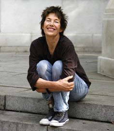 a woman sitting on steps with her arms crossed and looking at the camera, smiling