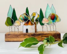 a group of stained glass trees sitting on top of a wooden stand next to a plant