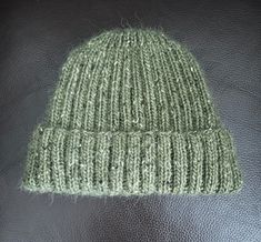 a green knitted hat sitting on top of a black leather chair