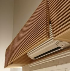 a white air conditioner sitting on top of a wooden shelf